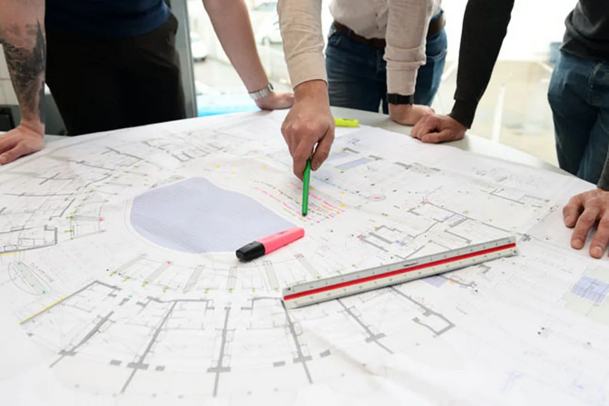 Détail des mains d’ingénieurs travaillant sur un plan technique de câblage électrique lors d’un reportage photo d’entreprise à Lyon