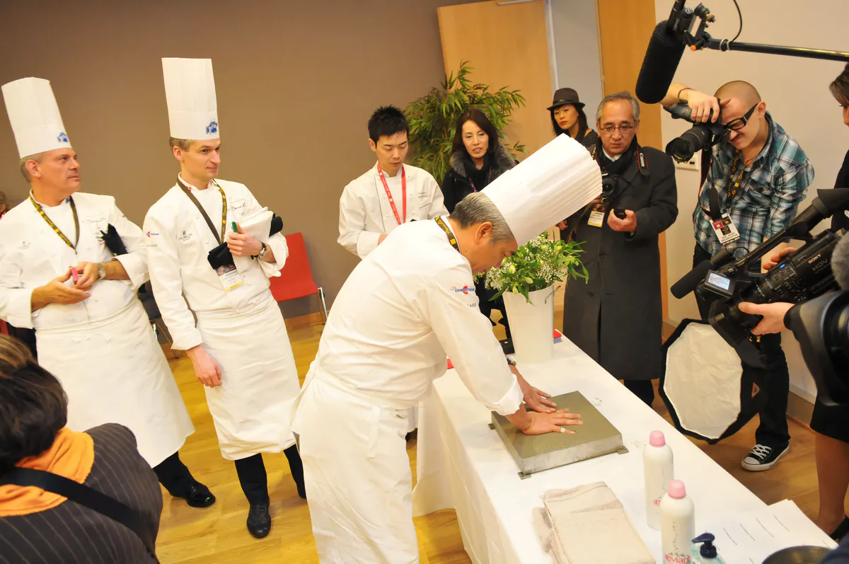 Un chef appose son empreinte de main lors de l’inauguration du Hall Paul Bocuse à Eurexpo Lyon, reportage photo événementiel avec présence médiatique