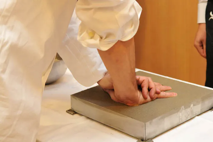 Détail des mains d’un chef apposant son empreinte dans le ciment lors de l’inauguration du Hall Paul Bocuse à Eurexpo Lyon