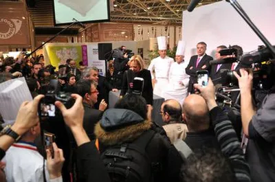 Paul Bocuse et des personnalités publiques face à une foule de photographes et de journalistes lors d’un événement institutionnel à Lyon
