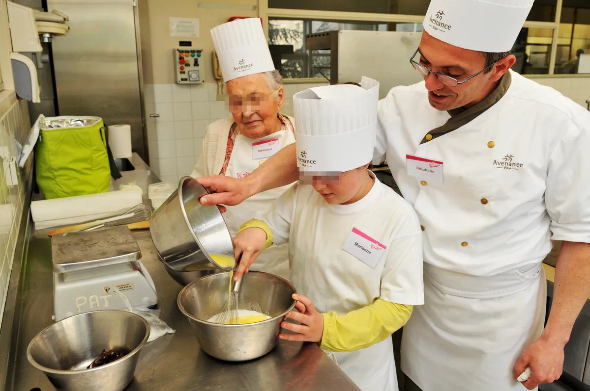 Concours culinaire intergénérationnel à l'École Bocuse : chef, enfant et senior collaborant en cuisine
