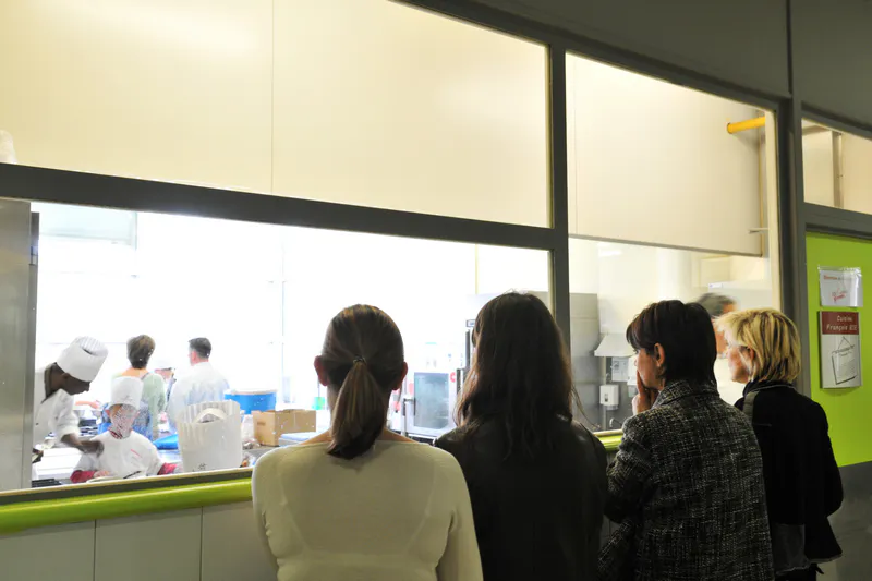 Membre du jury observant attentivement une équipe en pleine préparation culinaire