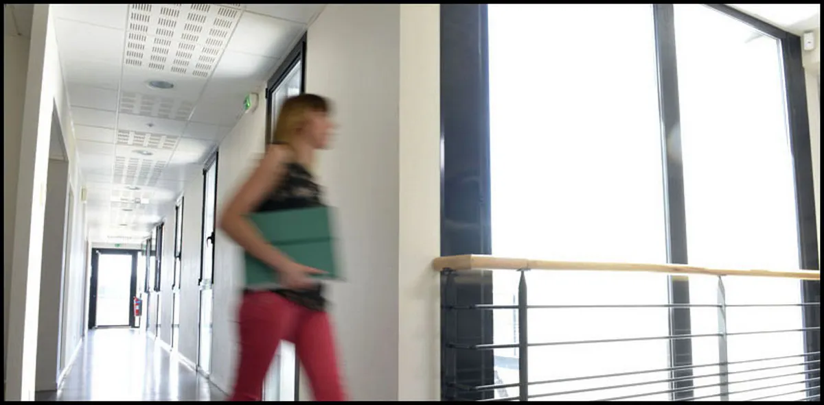 Femme se déplaçant dans un couloir d’entreprise avec une pile de dossiers, effet artistique de flou de mouvement