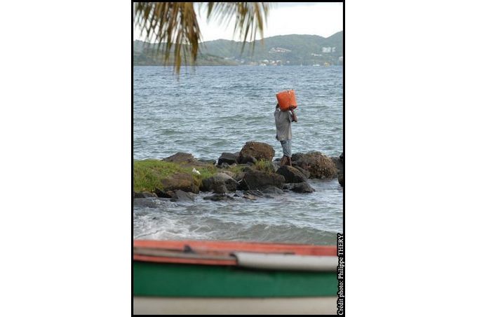bateau de pecheur et pecheur portant un baril sur jetee Martinique