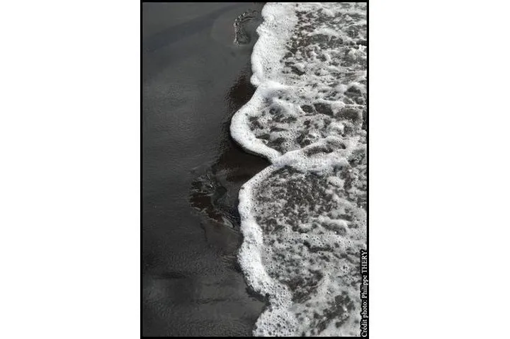 Détail d'une vague sur une plage de sable noir, Martinique